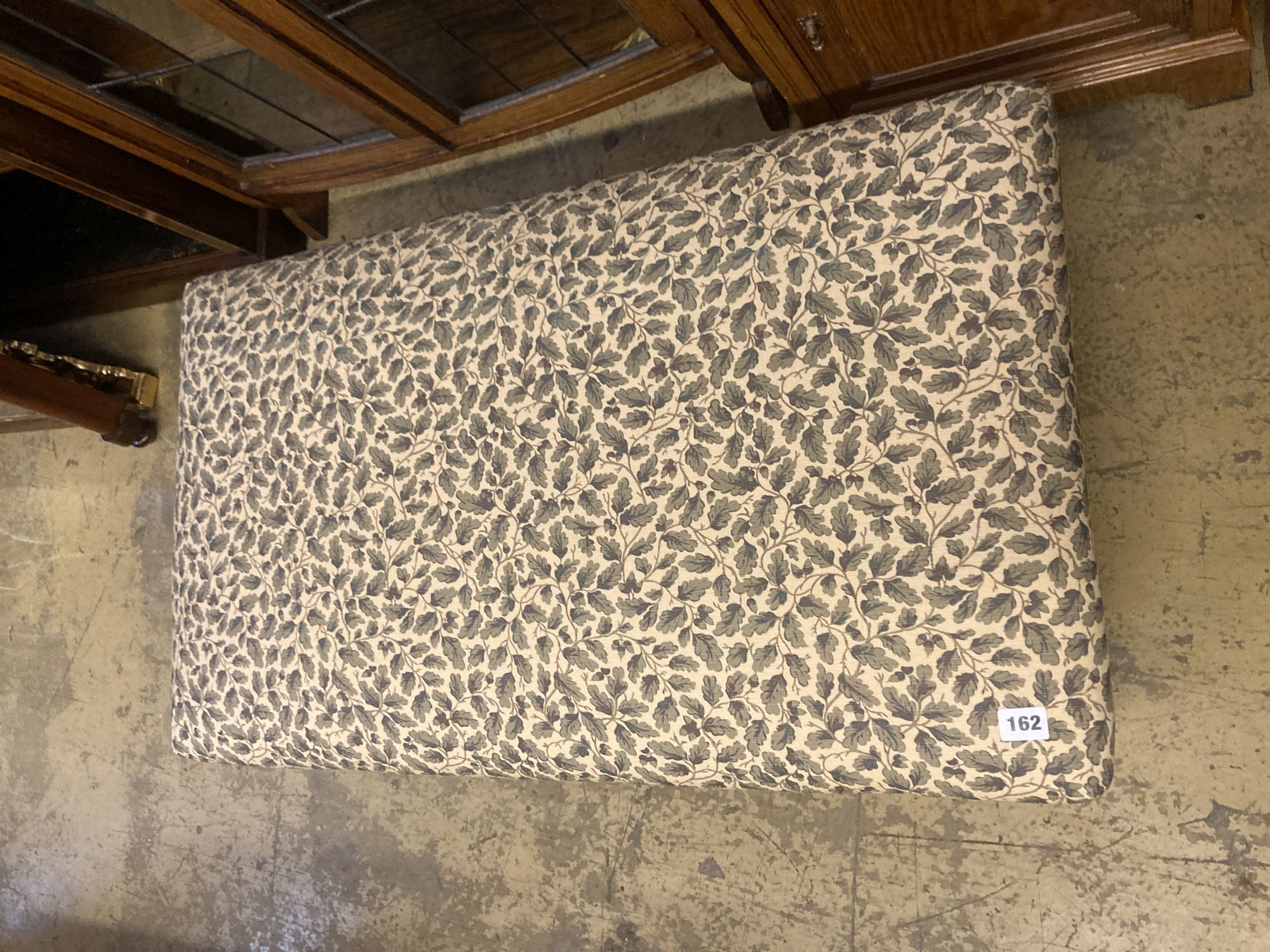 A modern rectangular footstool upholstered in a printed leaf fabric, width 90cm, depth 53cm, height 28cm